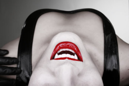 Sexy woman dressed as vampire, fangs and pale face